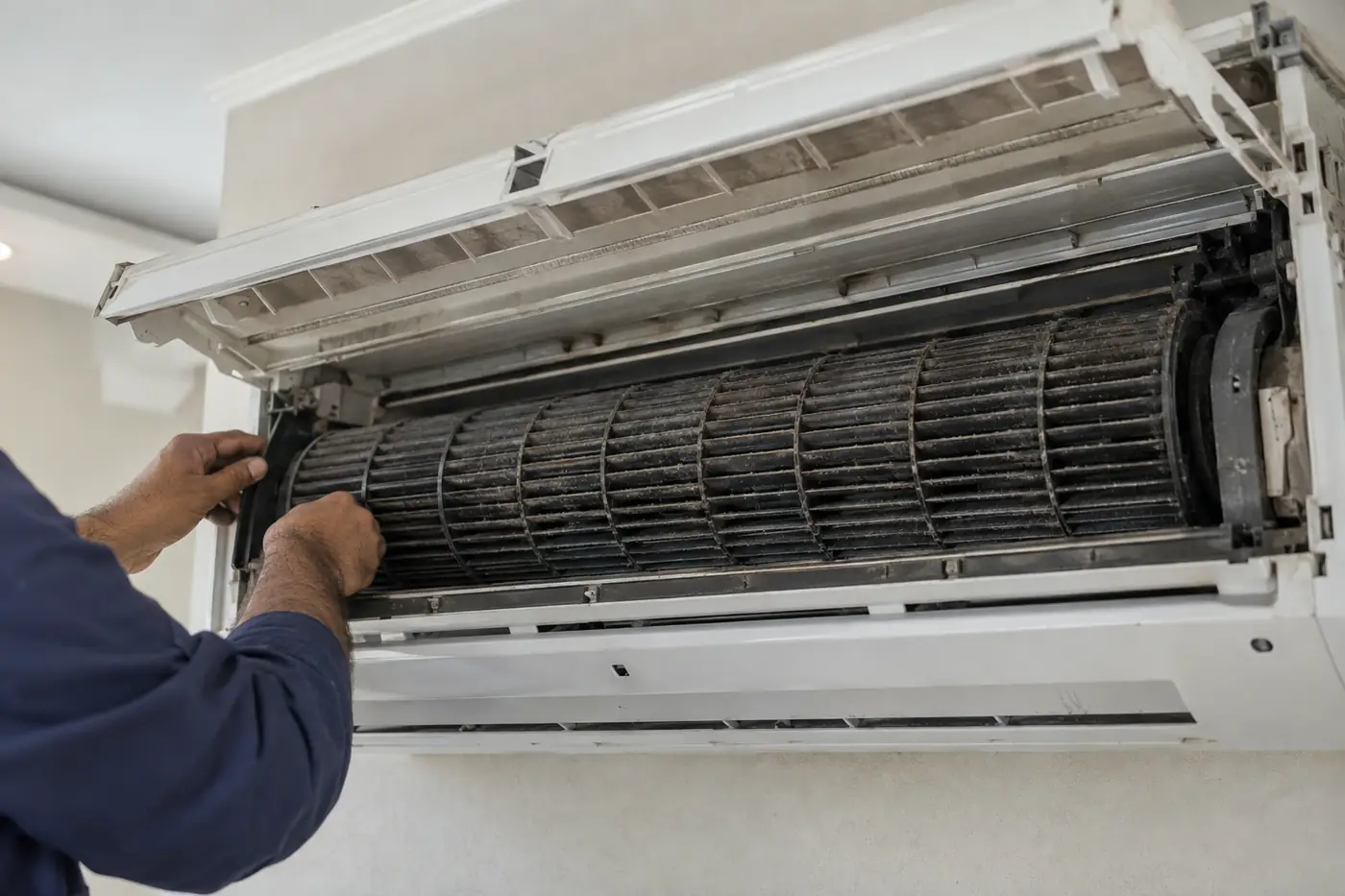 المروحة الأسطوانية داخل وحدة سبليت مفتوحة وعلى ريشها طبقة داكنة من الغبار والرطوبة